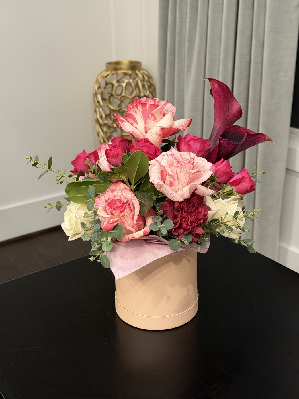 Blush hatbox of variegated pink roses, hot pink spray roses, white roses and a burgundy calla lily