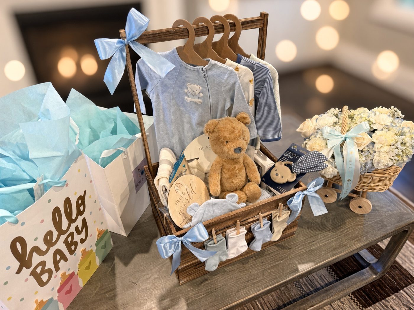 Baby boy gift crate with onesies on hangers, a teddy bear and socks on a clothesline