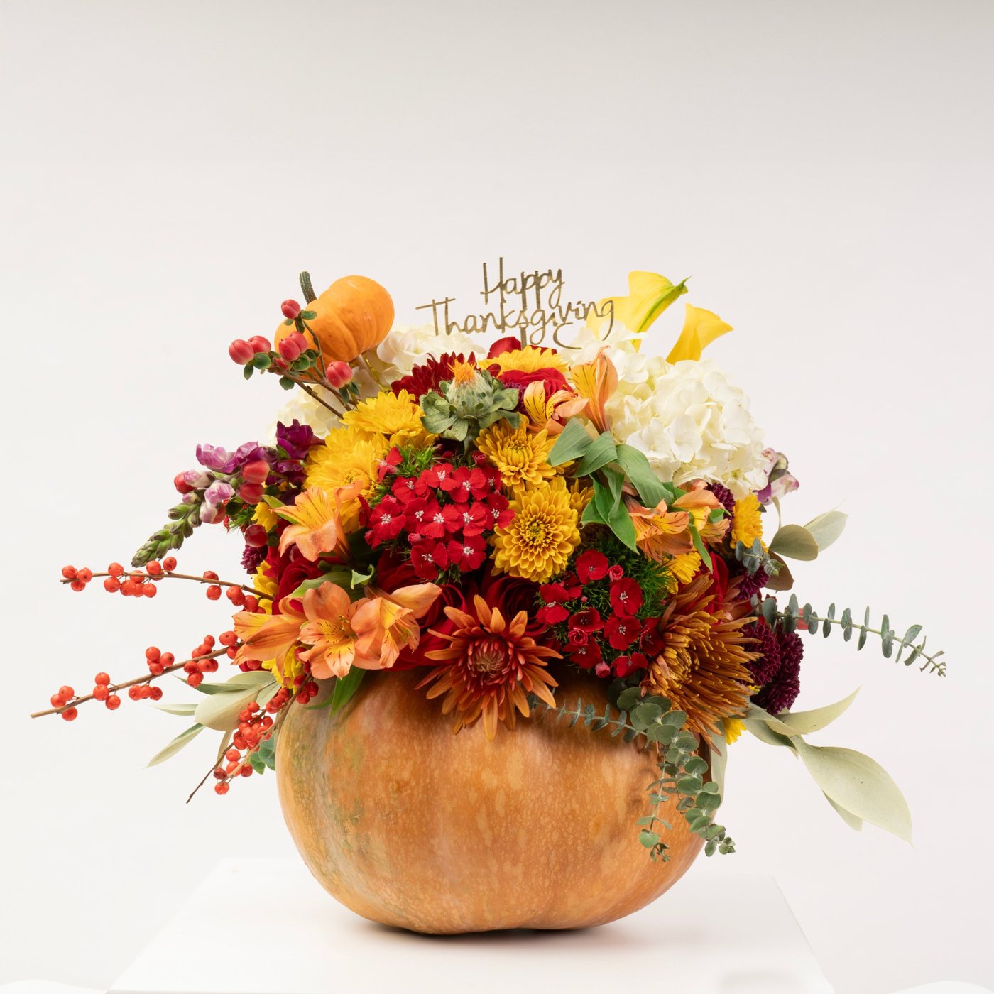 Thanksgiving arrangement of mums, alstroemeria, roses and berries in a real pumpkin