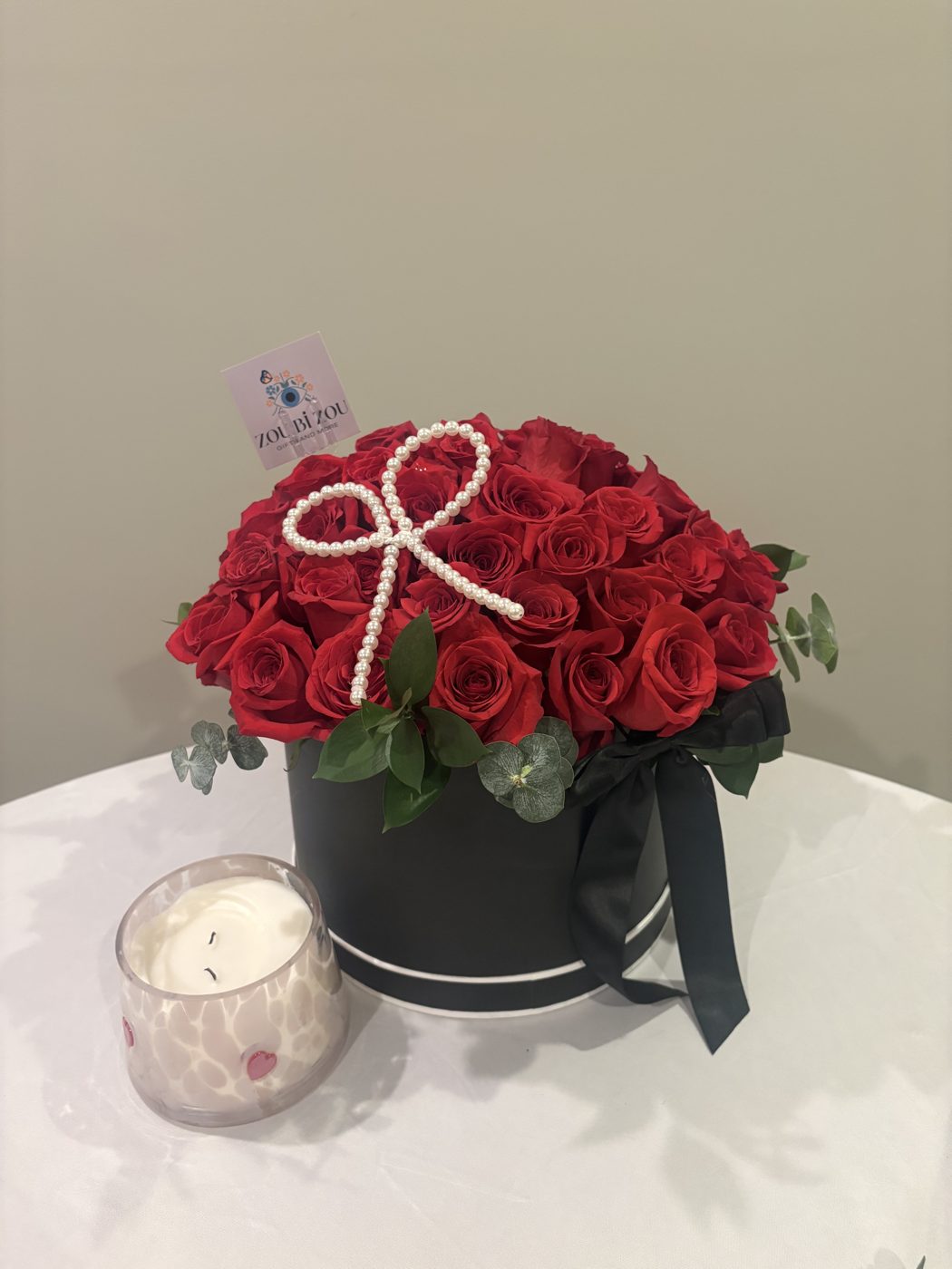 Hatbox of red roses tied with a pearl bow